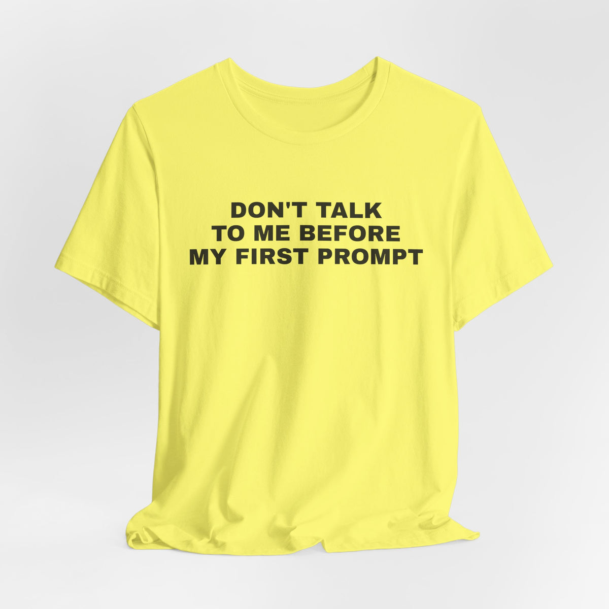 Yellow t-shirt printed with 'Don't talk to me before my first prompt'