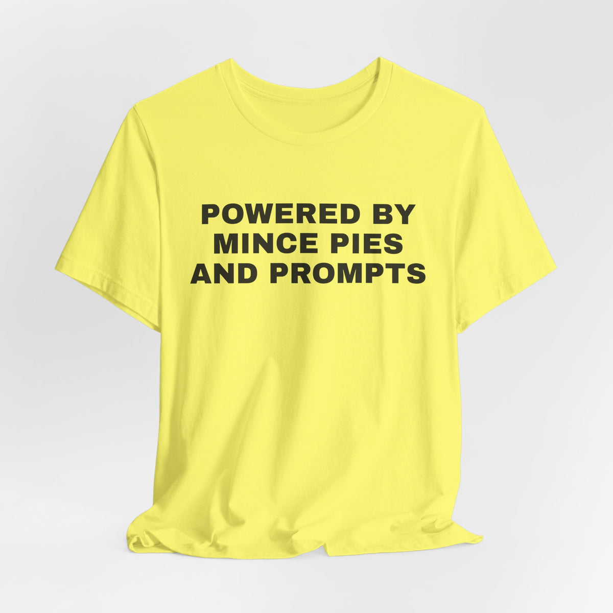 Yellow t-shirt printed with 'Powered by Mince Pies and Prompts'