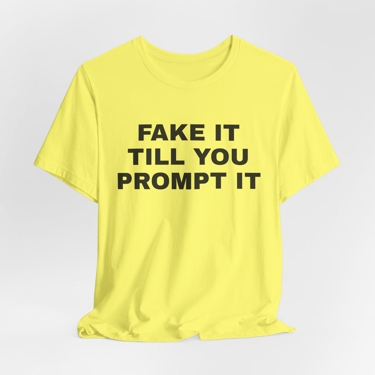 Yellow t-shirt printed with 'Fake it till you prompt it'
