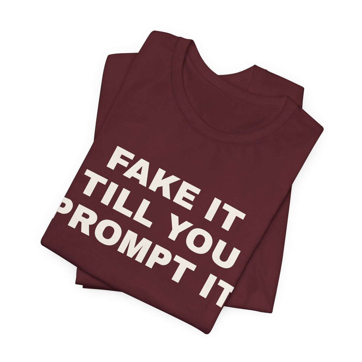 Maroon t-shirt printed with 'Fake it till you prompt it', folded