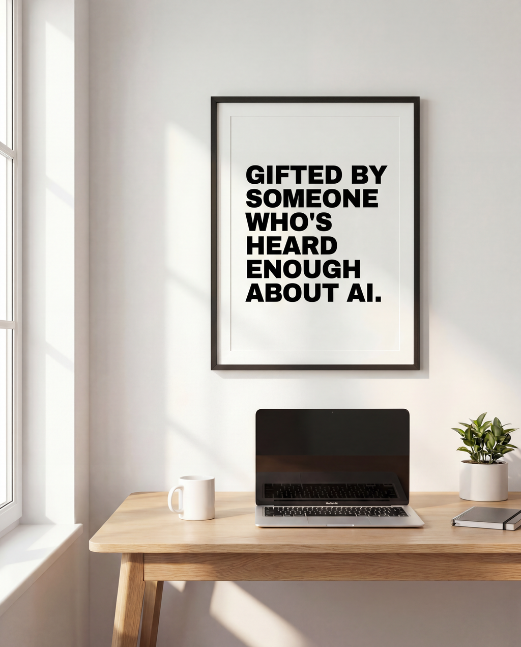 Framed wall print reading 'Gifted by someone who's heard enough about AI.', above a desk