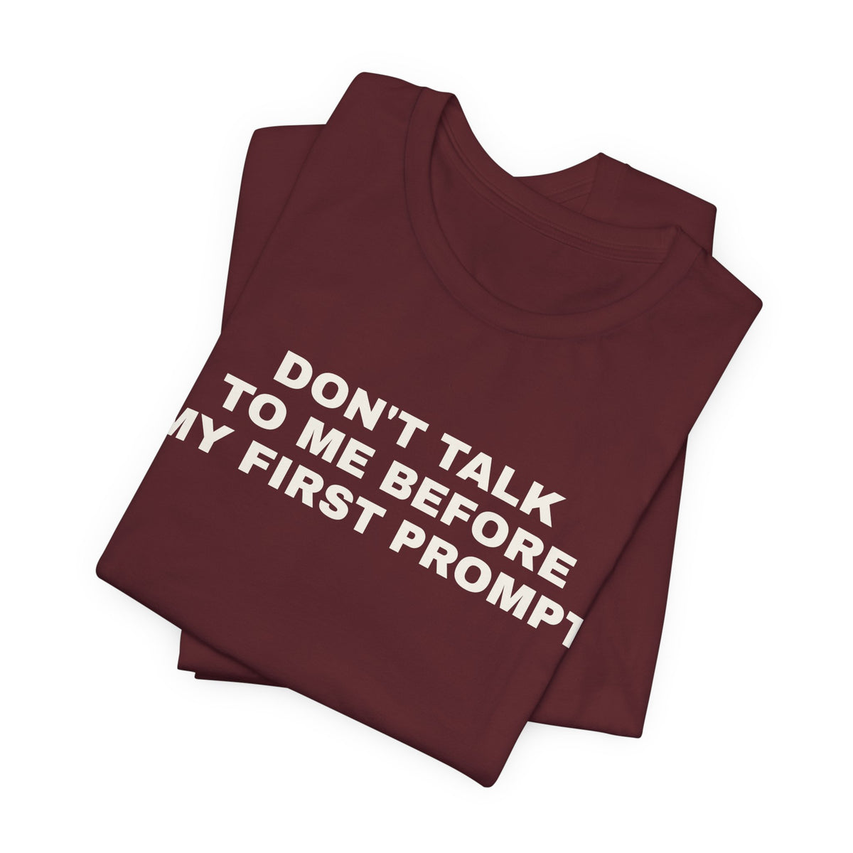 Maroon t-shirt printed with 'Don't talk to me before my first prompt', folded