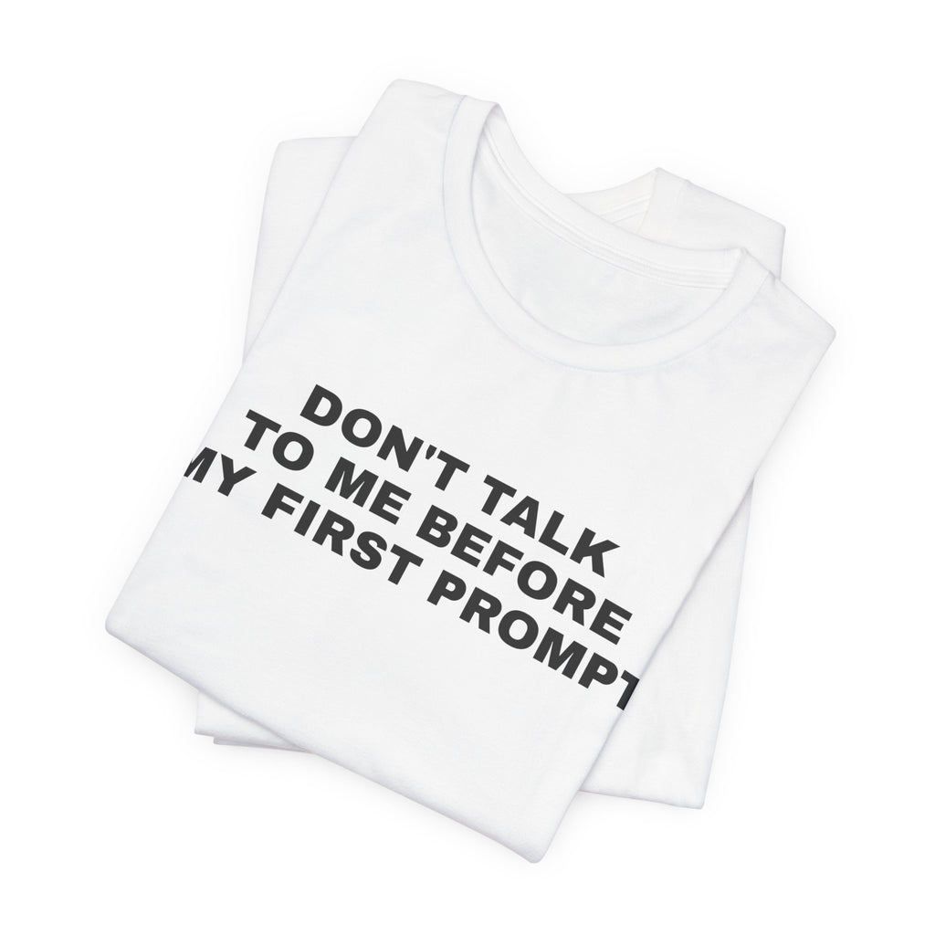 White t-shirt printed with 'Don't talk to me before my first prompt', folded