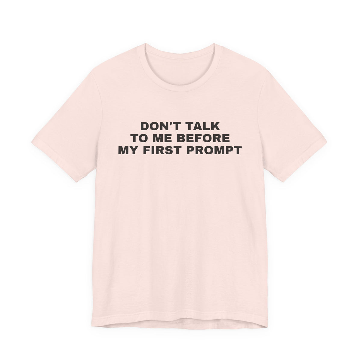 Soft pink t-shirt printed with 'Don't talk to me before my first prompt'
