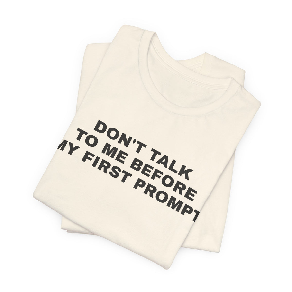 Natural t-shirt printed with 'Don't talk to me before my first prompt', folded