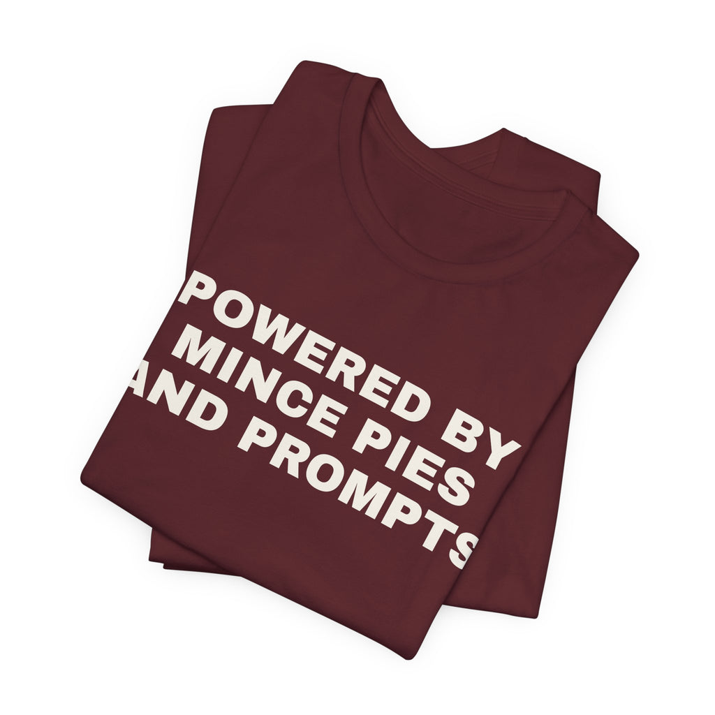 Maroon t-shirt printed with 'Powered by Mince Pies and Prompts', folded