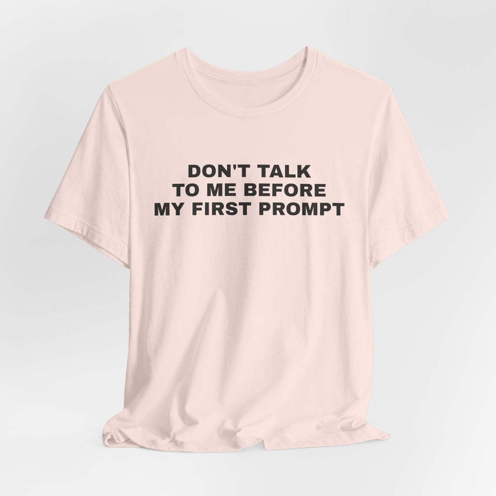 Soft pink t-shirt printed with 'Don't talk to me before my first prompt'
