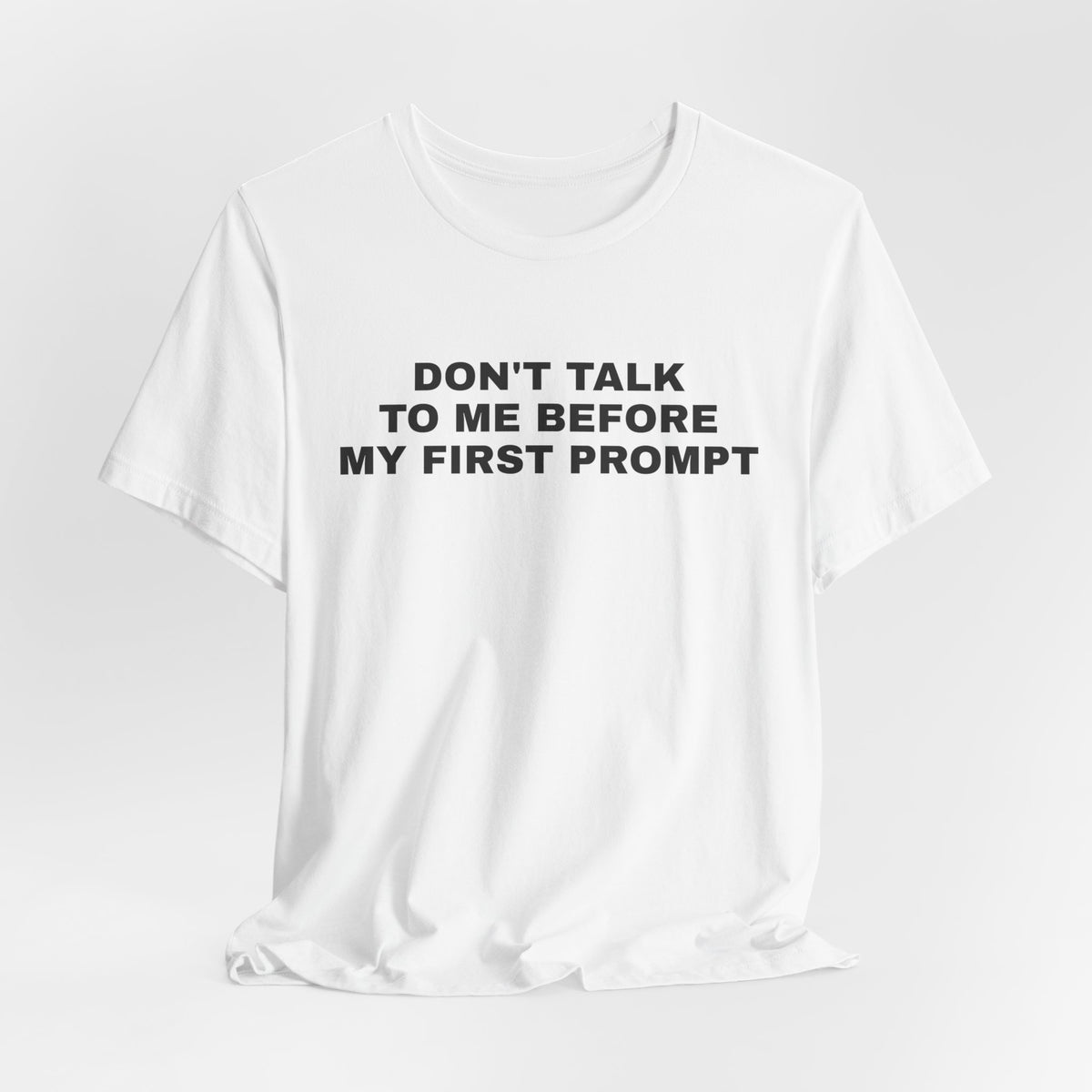 White t-shirt printed with 'Don't talk to me before my first prompt'