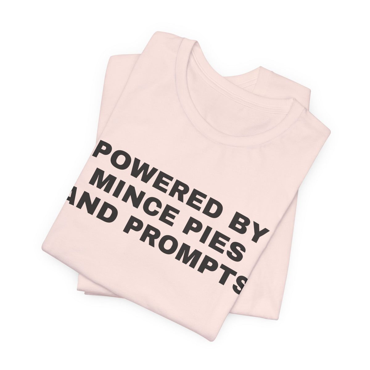 Soft pink t-shirt printed with 'Powered by Mince Pies and Prompts', folded